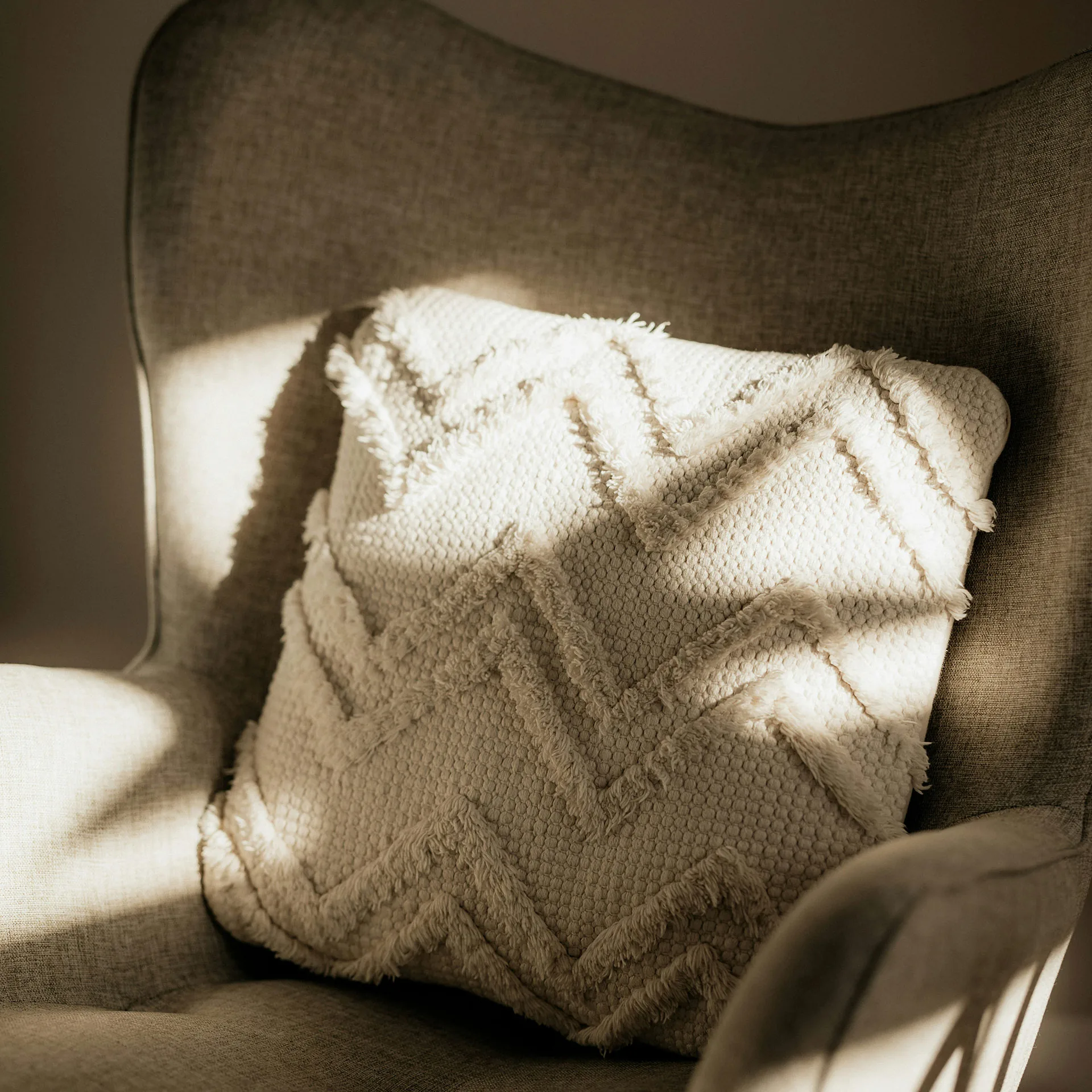 Närbild på ljus fåtölj med kudde